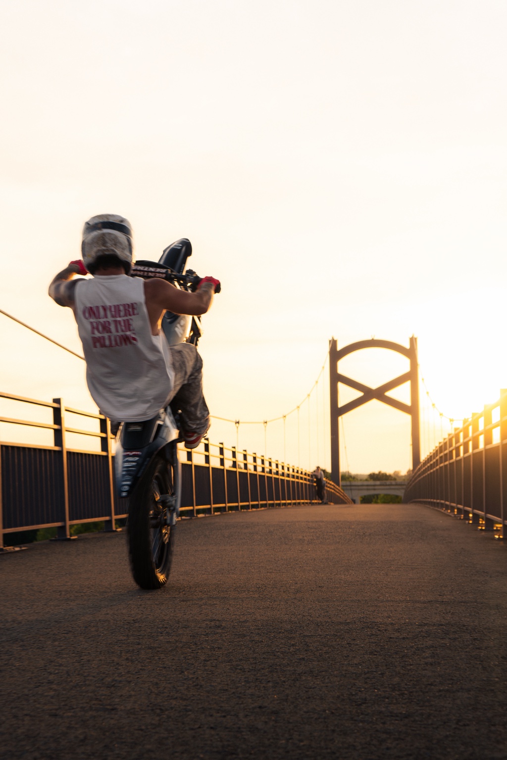 Motorcycle rider doing a wheelie on a bridge